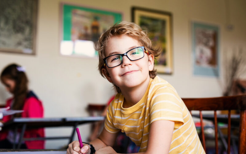 Blonde boy with glasses drawing. Group of elementary school pupils in classroom on art class. Russia, Krasnodar, May, 23, 2019.